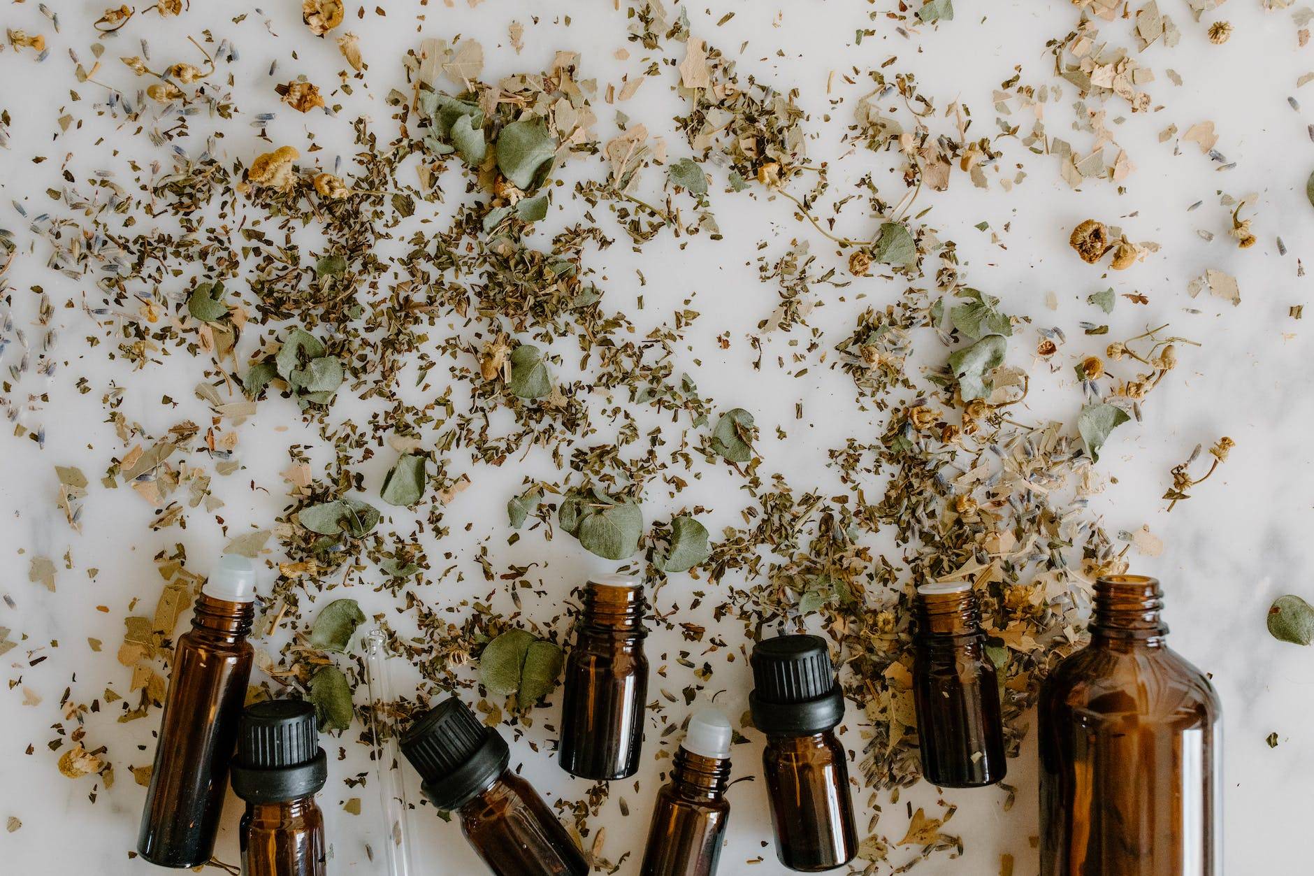 essential oil bottles and herbal medicine on white surface