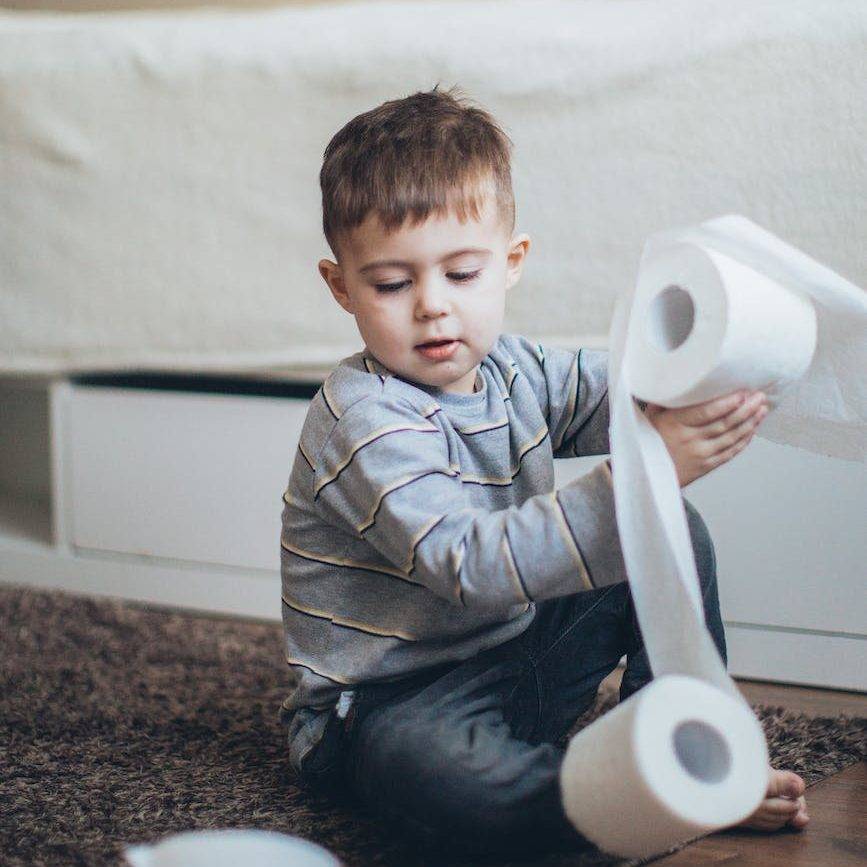 little boy playing with tissue rolls